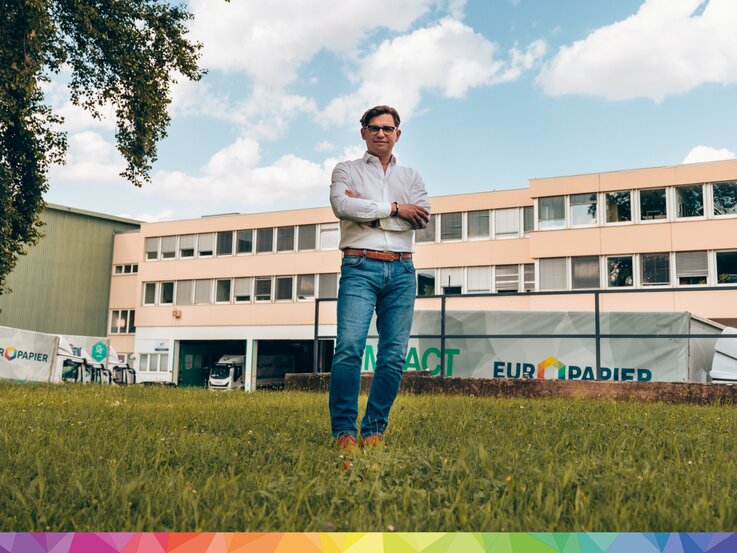 Mann steht auf Wiese vor Europapier Gebäude