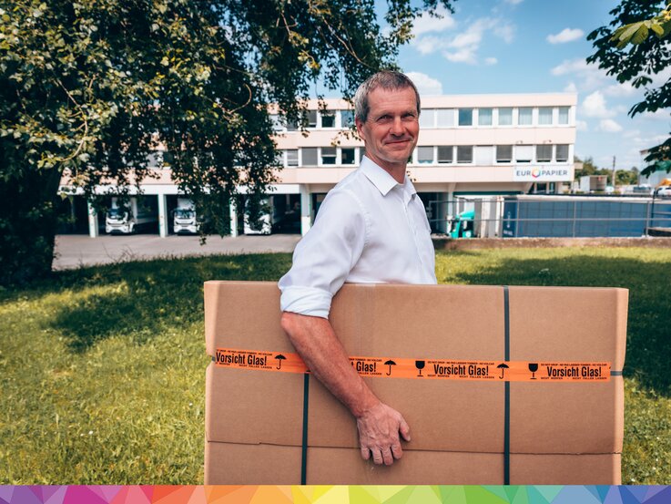 Mann trägt Karton vor Europapier Gebäude